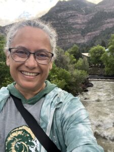 Selfie of owner of The West Coast Lady, Vanessa, with a background of mountains and river
